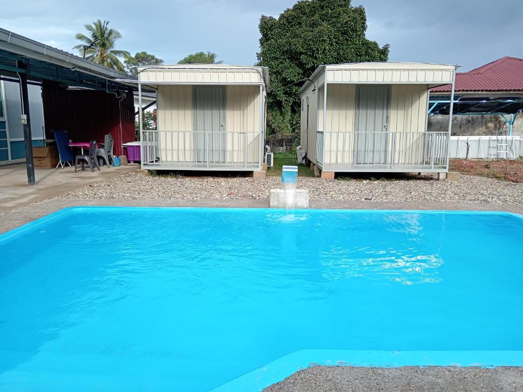 双溪大年Homestay Pinang Tunggal Cabin的蓝色游泳池,后面设有2间小屋