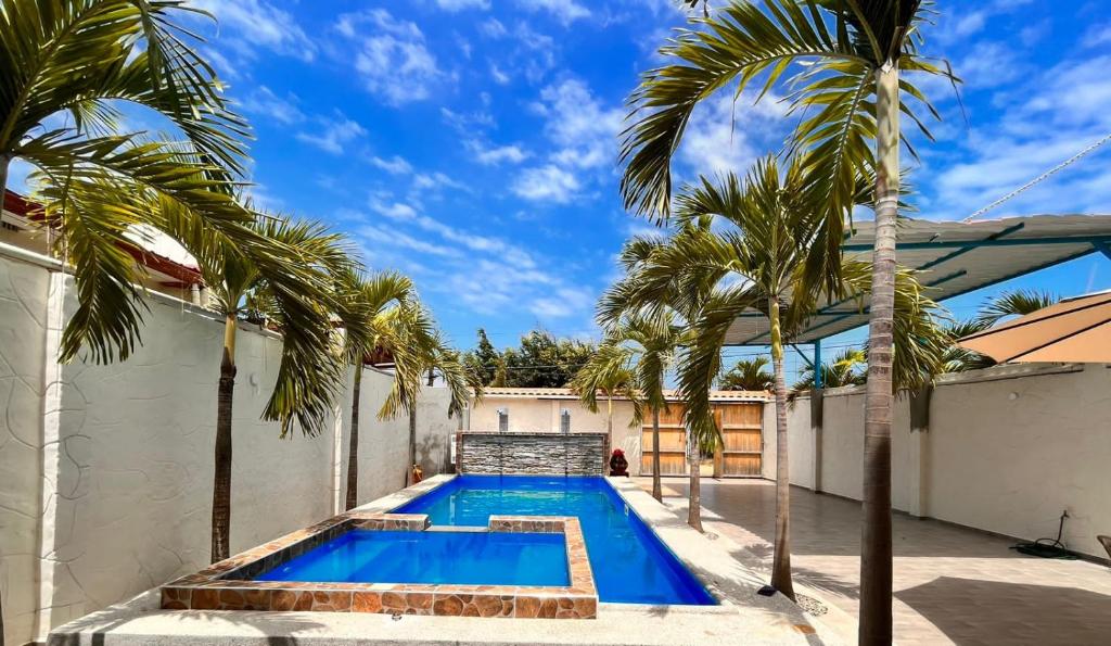 普拉亚斯Casa Halley #4 con vista al mar y piscina , 2 pisos - Villamil Playas , Data de Villamil的棕榈树房子后院的游泳池