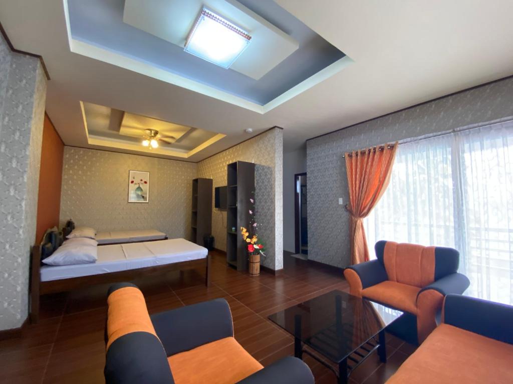 波尔多·格尼拉MinshukuKCS Hotel and Restaurant的一间卧室配有一张床、一张沙发和椅子