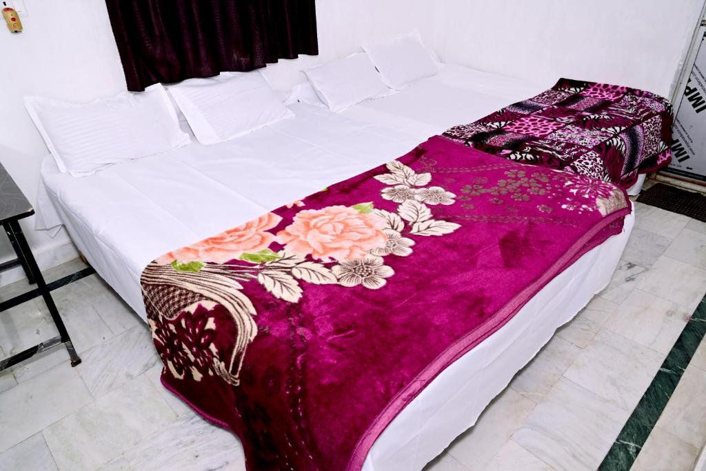 德奥加尔SHIVAY Guest House的白色的床,上面有紫色的毯子,上面有鲜花