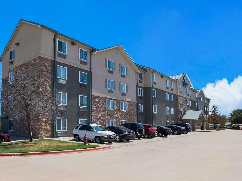 Trophy ClubWoodSpring Suites Fort Worth Trophy Club的大型公寓大楼,停车场有车辆停放