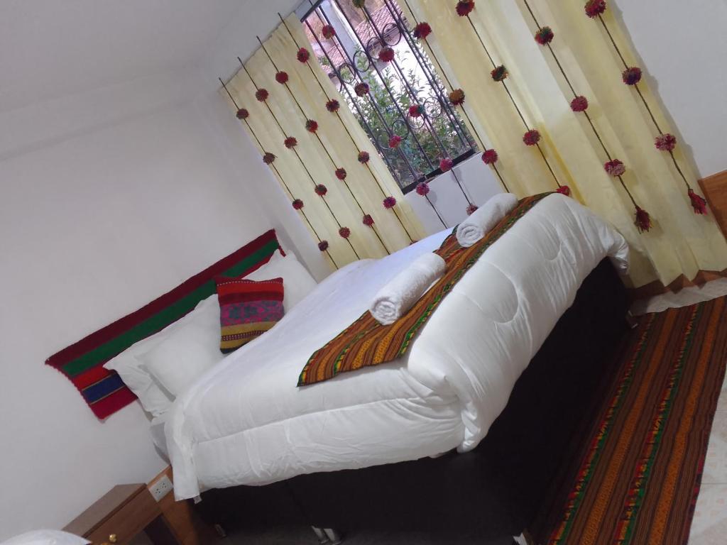 库斯科Incas Town Inn的一间卧室配有一张带白色床单的床和一扇窗户。