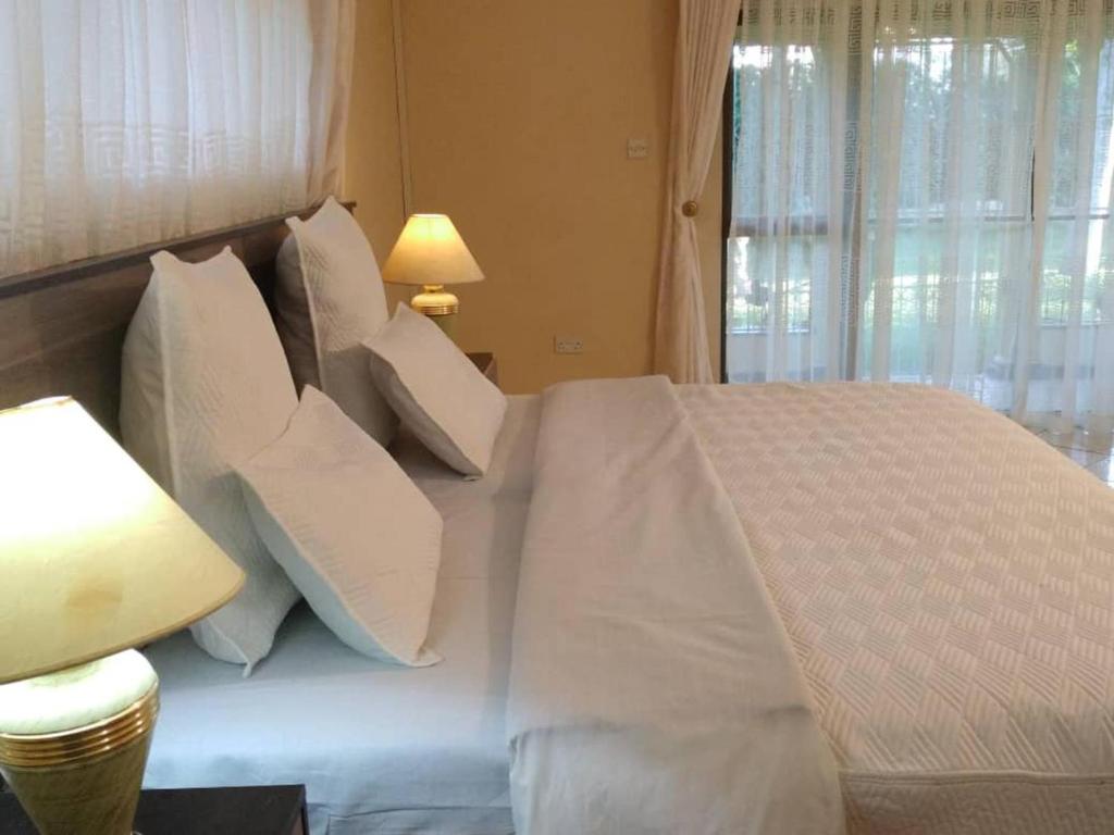 哈拉雷Charming 6-Bed House with Swimming Pool in Harare的一间卧室配有带白色床单和枕头的床。