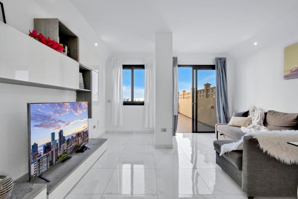 帕莱索海滩帕拉迪斯奢华公寓的白色的客厅配有电视和沙发