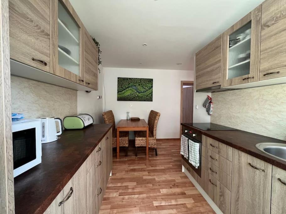 马汀Apartman centrum Šturka的厨房配有木制橱柜和带微波炉的桌子。