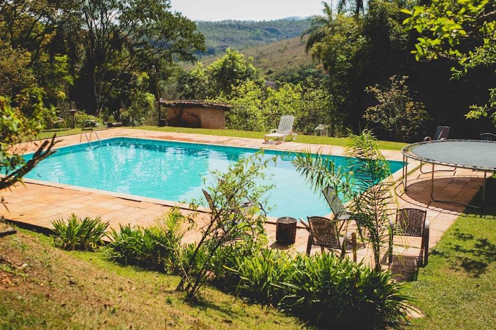 伊塔比里图Pousada Suçuarana的庭院内的游泳池,配有桌椅