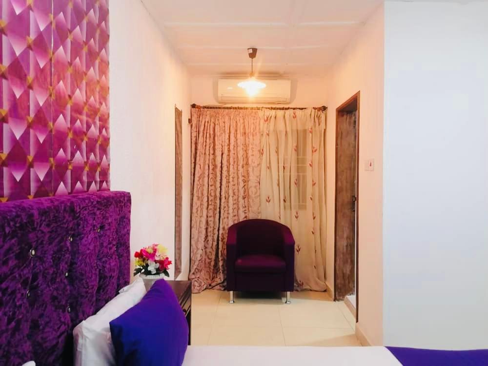 弗里敦ZUNOX GUEST HOUSE的一间设有椅子和紫色墙壁的房间