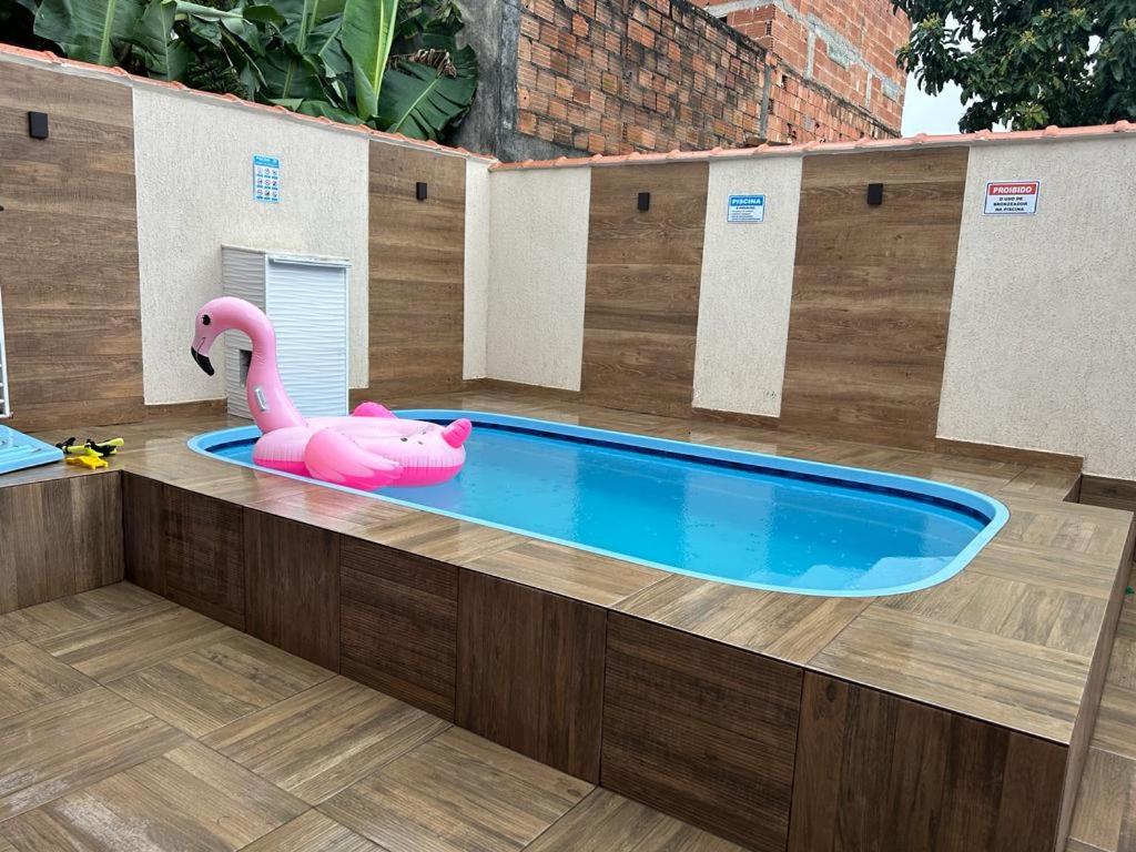 大伊瓜巴Casa iguaba com área de lazer的木制甲板上的游泳池及其粉红色火烈鸟