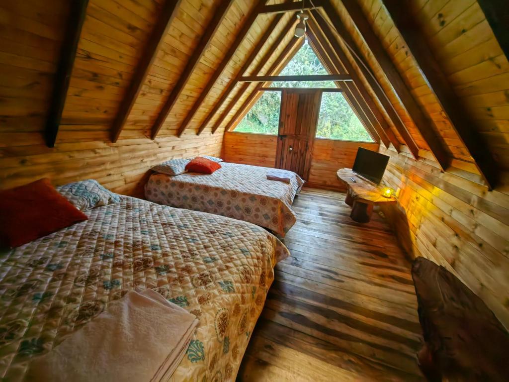 乔阿奇Cabañas del bosque的小木屋内一间卧室,配有两张床