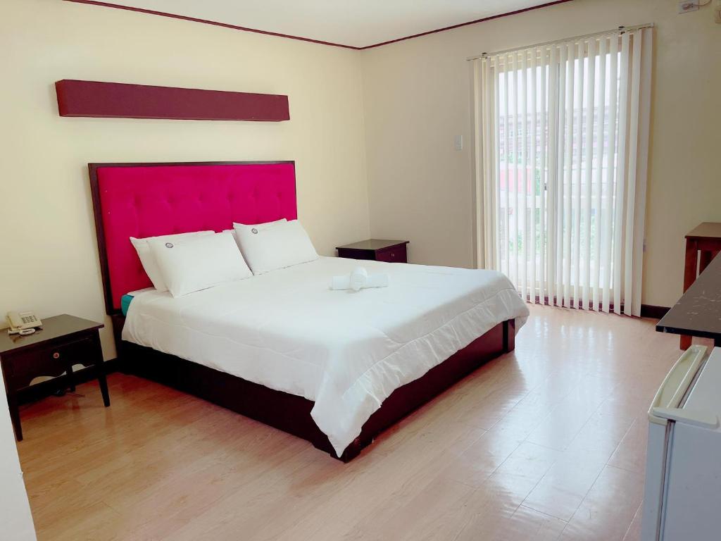 安吉利斯Jun and Helen Hotel and Restaurant的一间卧室配有一张大床和红色床头板