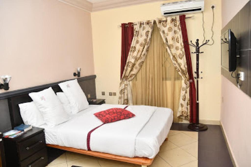 贝宁城Room in Lodge - Choice Gate Hotel-Business Double的一间卧室配有一张红色枕头的床