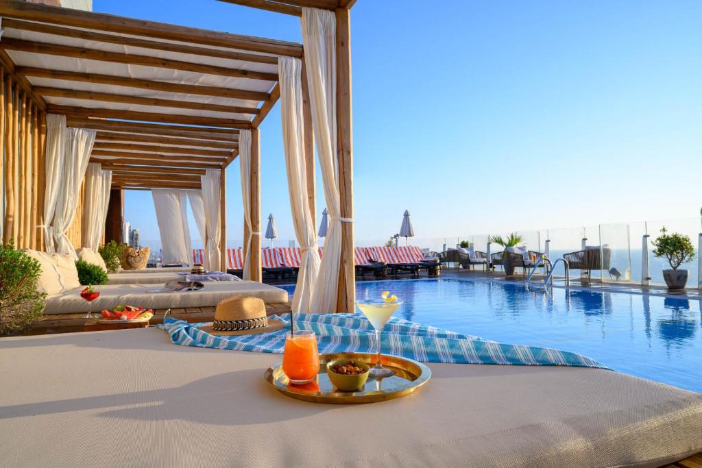 特拉维夫卡尔顿特拉维夫酒店 - 海滩豪华型的一张桌子,旁边是游泳池,上面有盘子