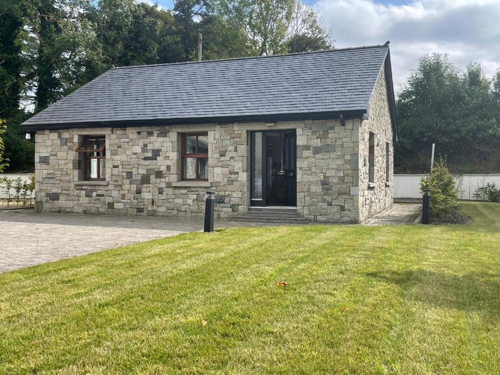 卡斯尔巴Creevagh Cottage的一座带草地庭院的小石头房子