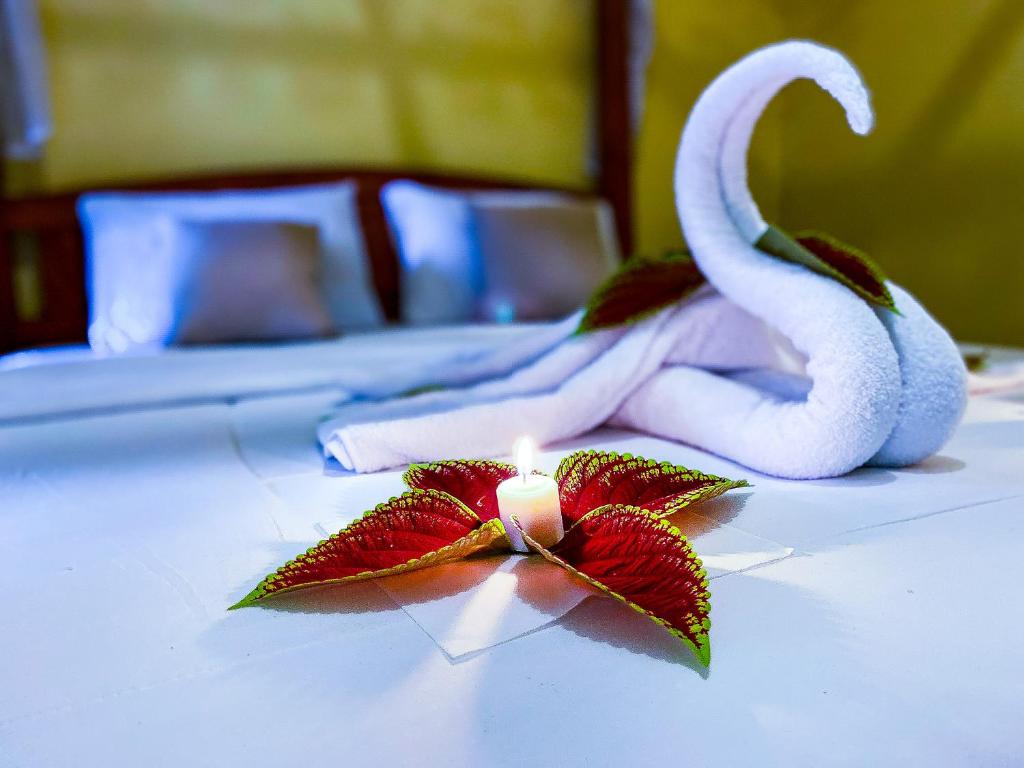 新加拉惹Ananda Homestay Lemukih的床上的蜡烛,带毛巾和花