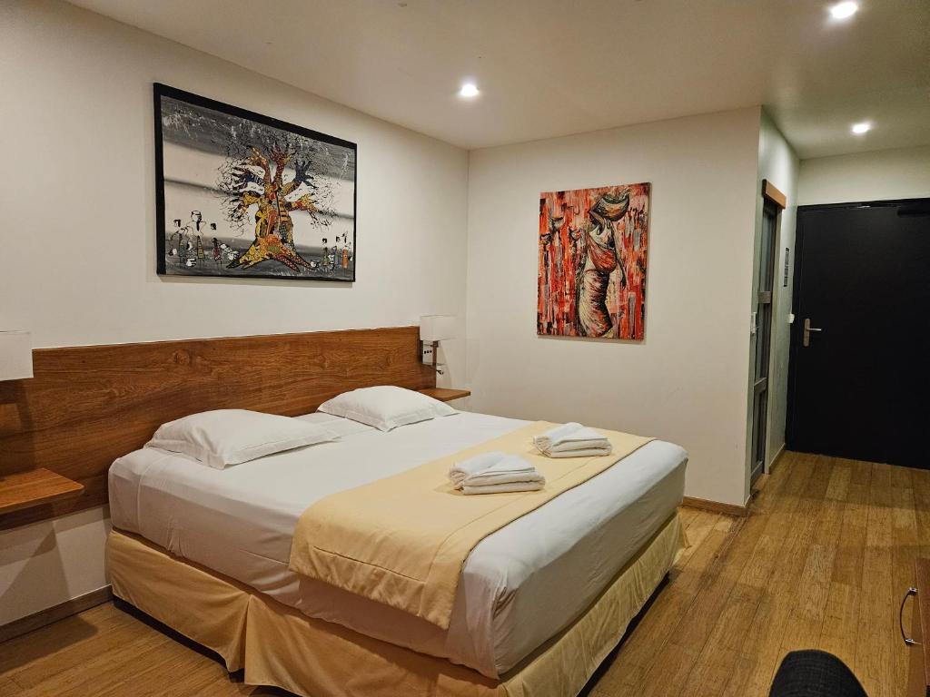 库鲁SAS CLP - La Marina的卧室配有一张大床,墙上挂有绘画作品