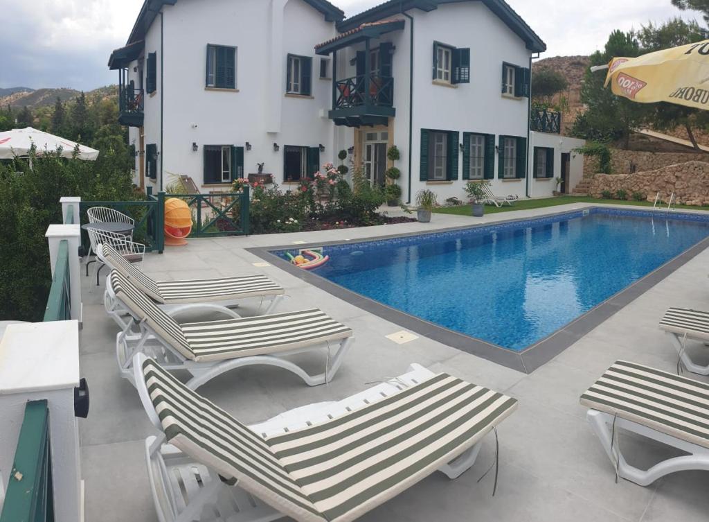 Lefke-KaradağDervise Mehmet Guest House的一个带躺椅的游泳池以及一座房子