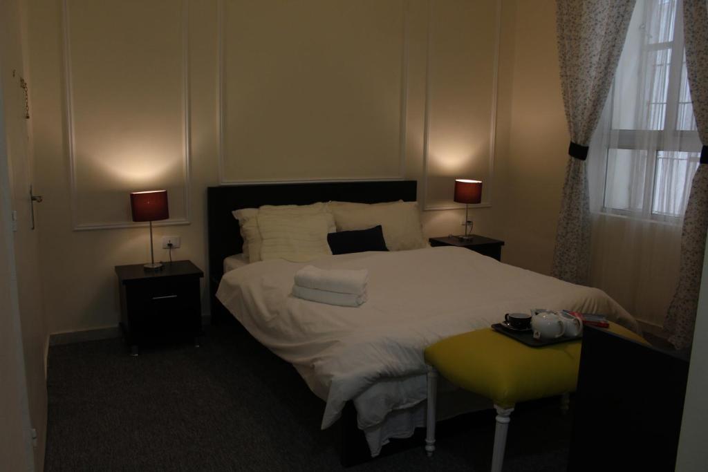 安曼The 1st Night Hotel的一间卧室配有一张带两盏灯和一张黄色凳子的床。