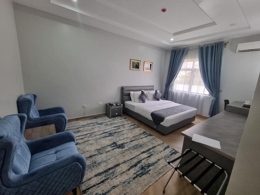 MaiduguriSolace Suites and Homes Maiduguri的一间卧室配有一张床、两把椅子和一张桌子