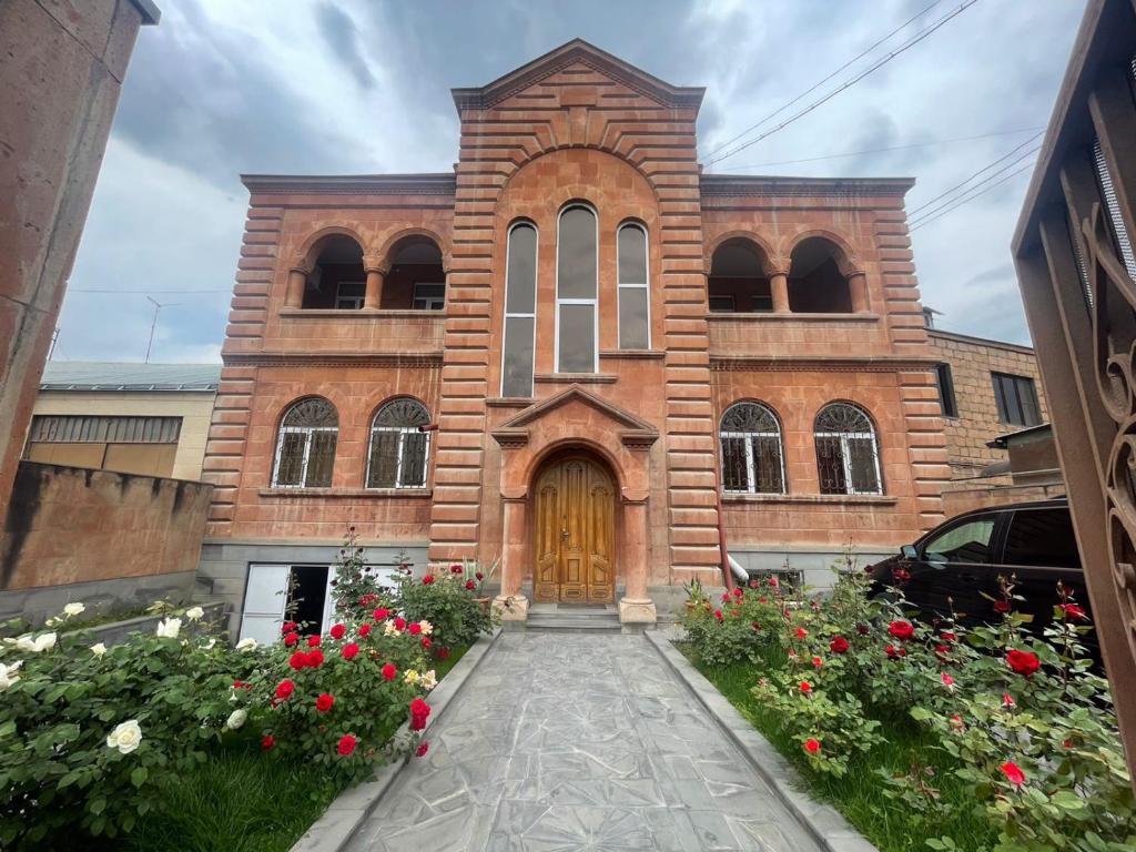VagharshapatNajaryan's Family Guest House的砖砌教堂,有木门和鲜花
