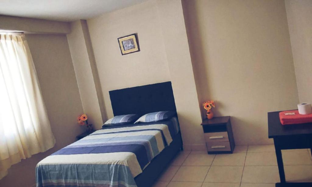 皮乌拉Hospedaje Residencial Los Fresnos - Miraflores Piura的一间卧室配有一张床、一张书桌和一个窗户。