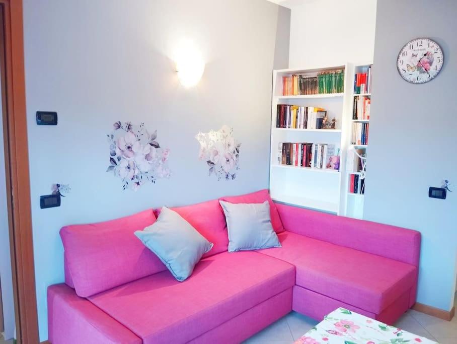 布斯托阿西齐奥il Sole di Busto APT的客厅里一张粉红色的沙发,配有书架