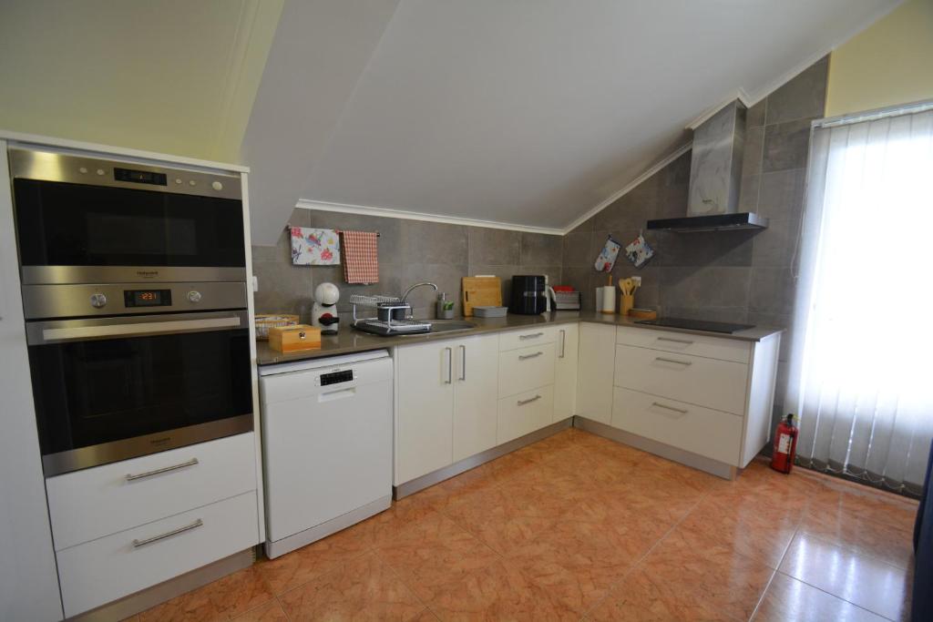 奥尔塔Casinha das Hortênsias的厨房配有白色橱柜和不锈钢用具