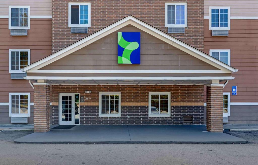 亚特兰大Extended Stay America Select Suites - Atlanta - Chamblee的红砖建筑,上面有蓝色和绿色的标志