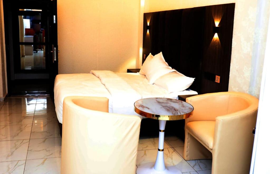 PokuaseTexas Royal Hotel的酒店客房,配有床、桌子和椅子