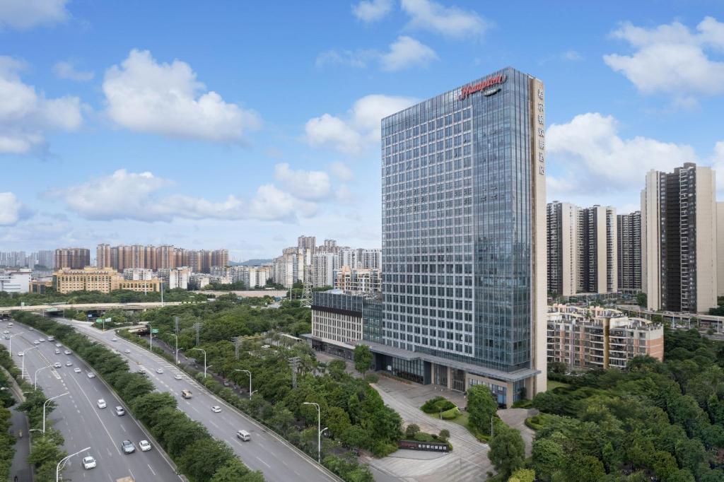 南宁南宁江南希尔顿欢朋酒店的一座高大的玻璃建筑,在有公路的城市里