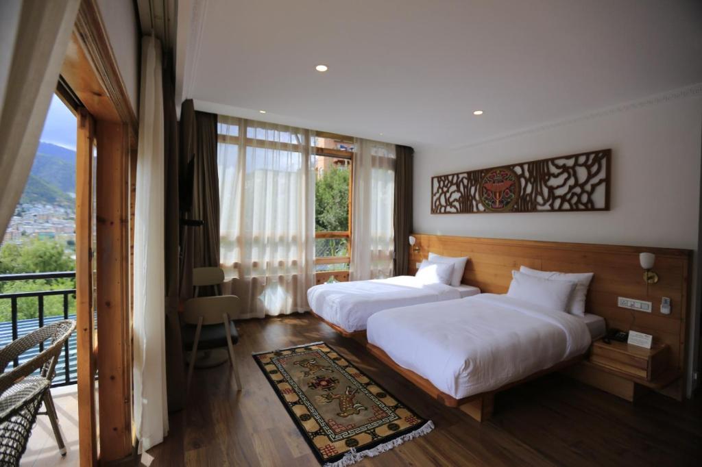廷布Phuntsho Khangsar Hotel的带阳台的酒店客房内的两张床