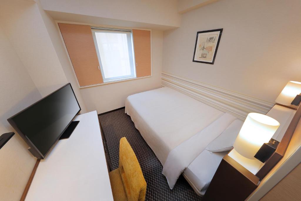东京Keio Presso Inn Shinjuku的酒店客房配有一张床和一张书桌及一台电视