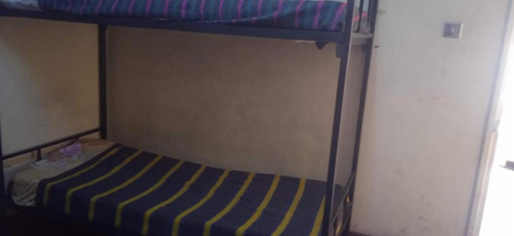 内罗毕Kioneki hostels的一张带蓝色和黄色条纹床垫的双层床
