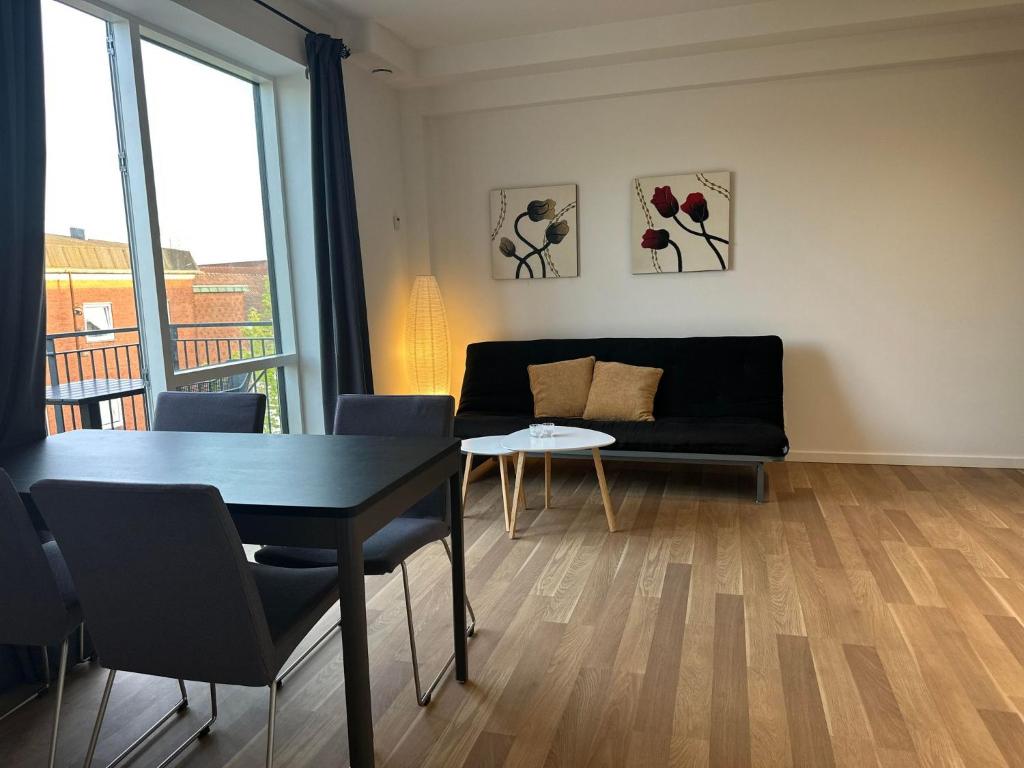 瓦埃勒City Apartment Dæmningen Vejle的客厅配有黑色沙发和桌子