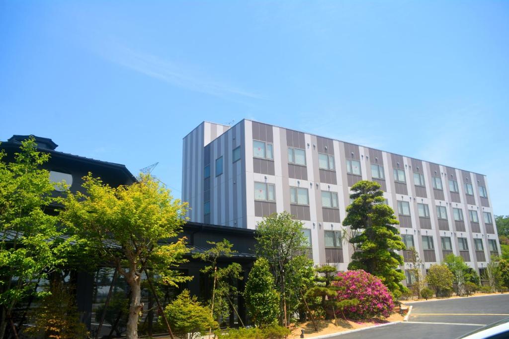 广野町Hotel Futabatei的一条高大的白色建筑,在街道前有树木