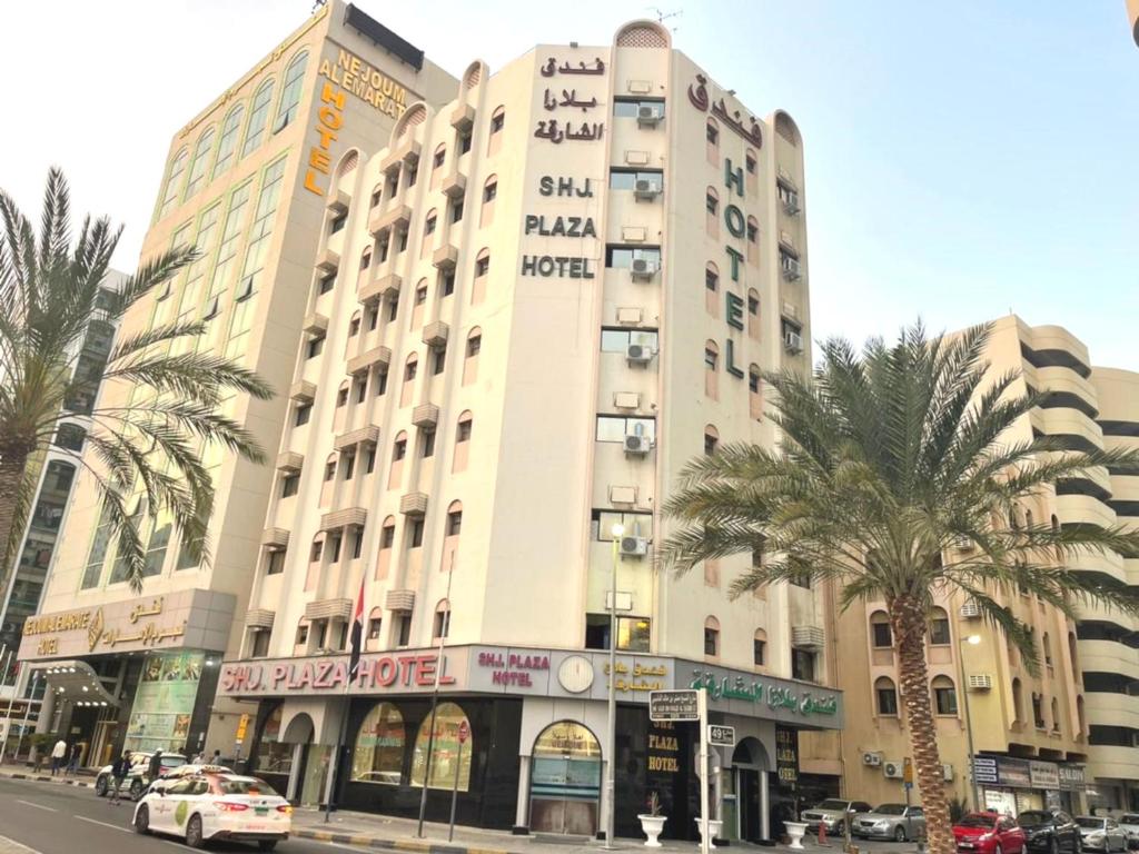 沙迦Sharjah Plaza Hotel的一座种植了棕榈树的城市街道上的大型建筑