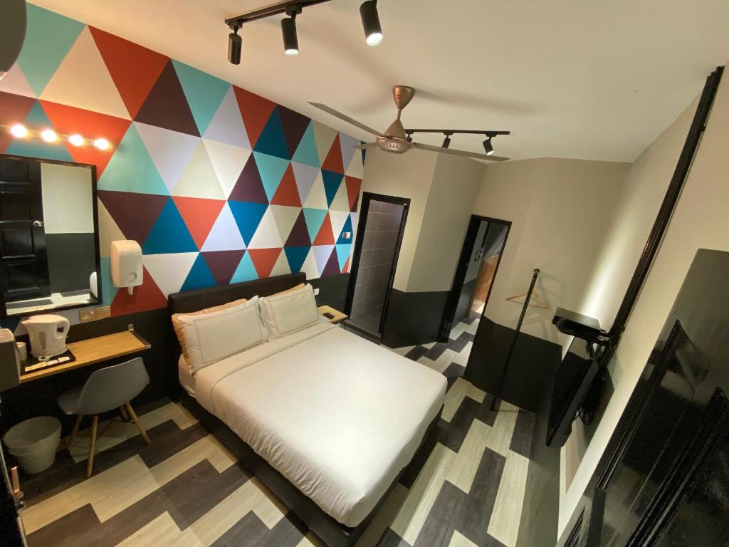 伯恩仓Kavy Boutique Hotel @ KBH的一间卧室配有一张床、一张书桌和色彩缤纷的墙壁