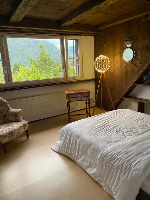 MoutierLa maison du petit bonheur的卧室配有床、椅子和窗户。