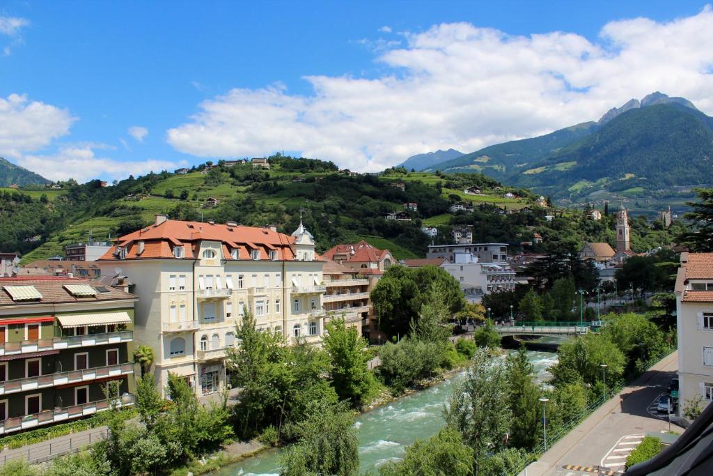 梅拉诺曼佐尼客房酒店的一座以河流和山脉为背景的城市