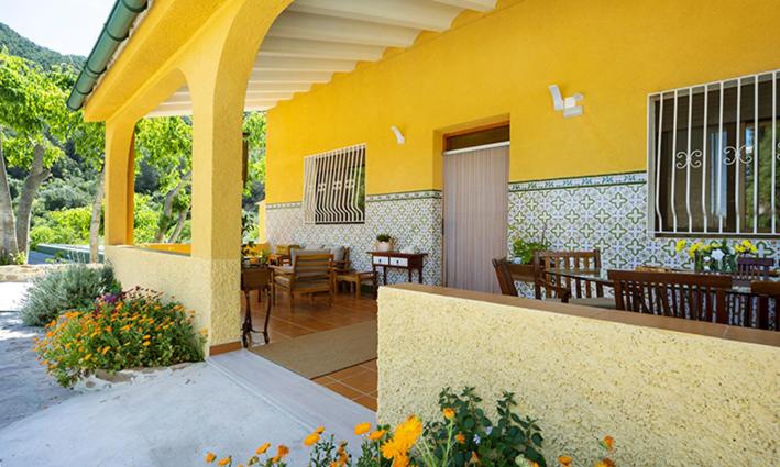 EslidaParaíso Cuántico的黄色的建筑,设有配备桌椅的庭院