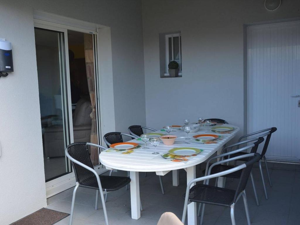 圣吉尔-克鲁瓦德维Maison Saint-Gilles-Croix-de-Vie, 4 pièces, 7 personnes - FR-1-224-32的餐桌、椅子、带盘子和玻璃杯的白色桌子