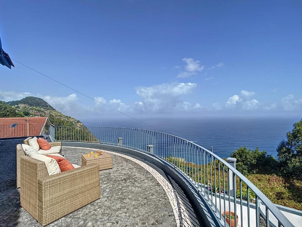 莫尼兹港Vinhaticos Villa by Atlantic Holiday的俯瞰大海的阳台上的藤椅