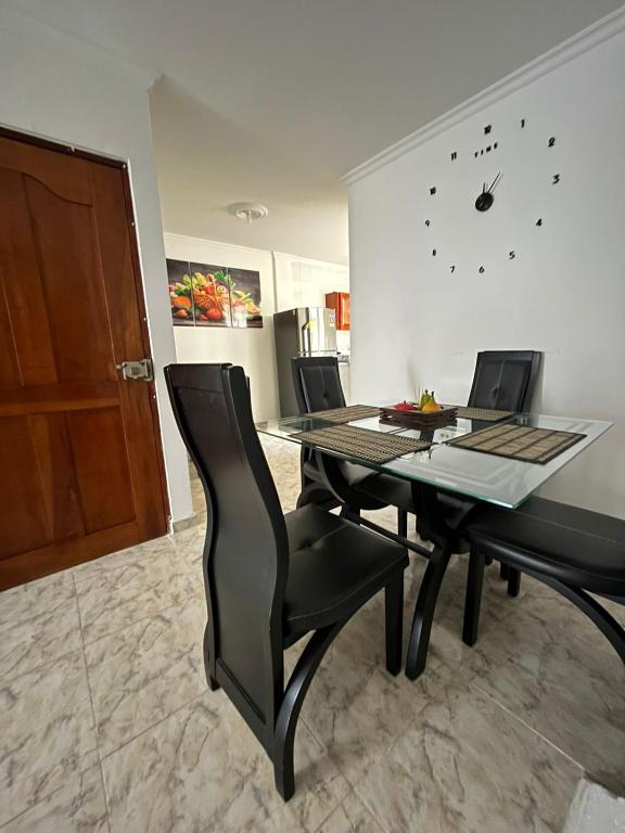 卡塔赫纳Apartamento Vacacional Cartagena Colombia的一间带桌椅和时钟的用餐室