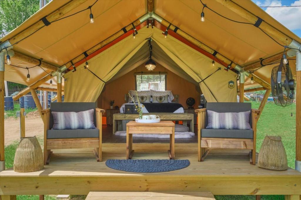 NavasotaIn A Meading - Safari Tent - BeeWeaver Honey Farm的帐篷配有1张床、2把椅子和1张桌子