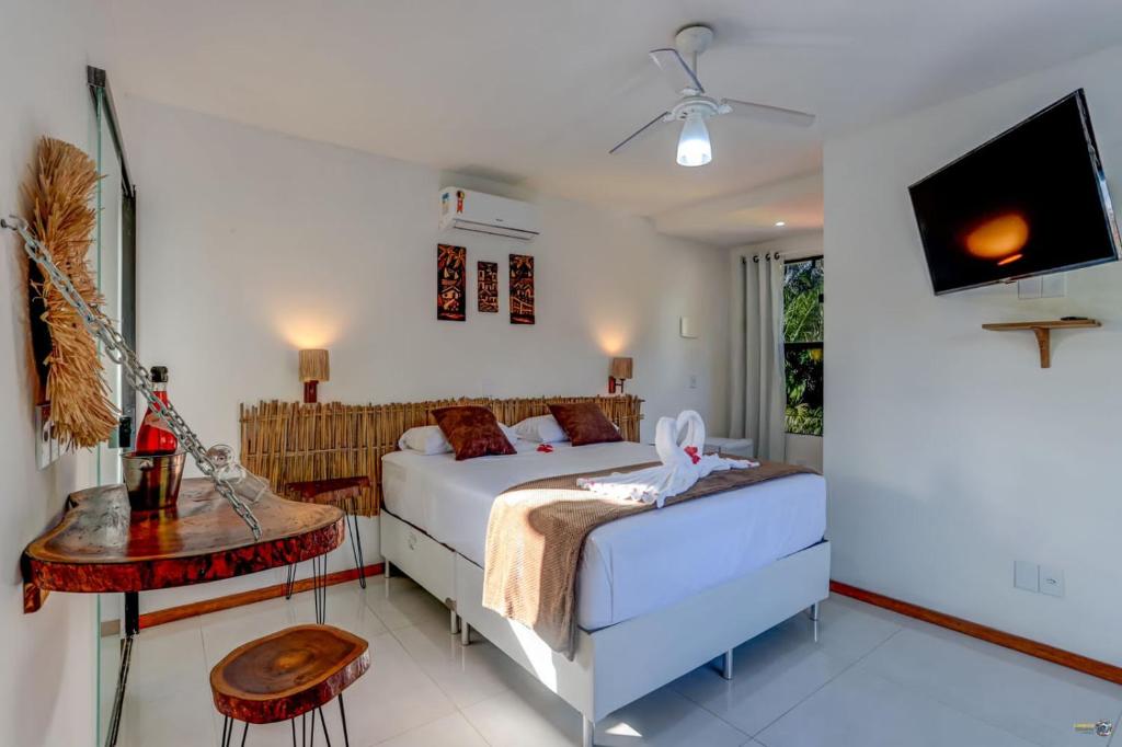 伊塔卡雷Pousada Endlessenses的一间卧室配有一张床、一张桌子和一台电视。