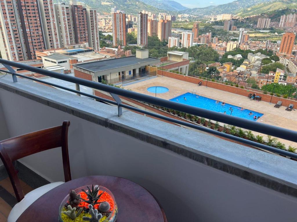 贝约Hermoso Apto con Vista al Ciudad y Parqueadero Gratis的阳台配有桌子,享有游泳池的景色