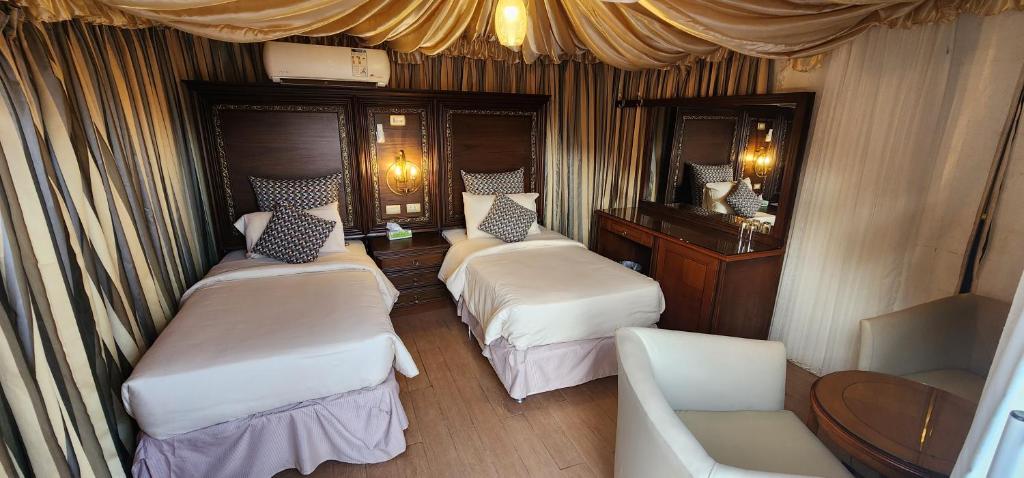 瓦迪拉姆Go bedouin camp的带三张床、椅子和镜子的客房