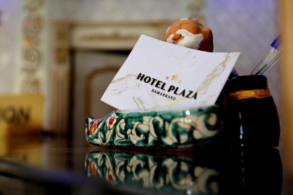 撒马尔罕Hotel Plaza 777的一张桌子,上面有酒店广场标志和糕点