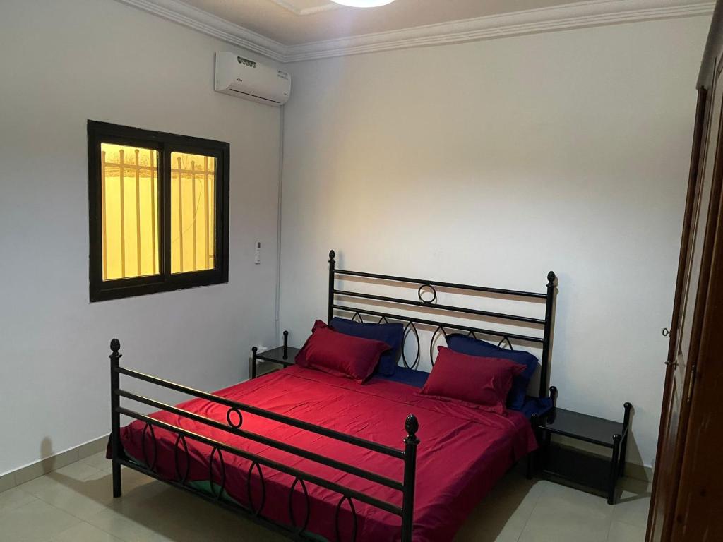 达喀尔Villa sokhna ndeye mbacke的一间卧室配有一张带红色床单的床和一扇窗户。