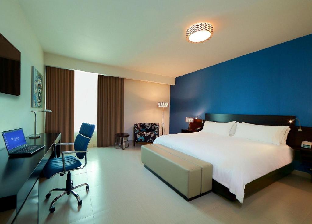 巴拿马城巴拿马城汉普顿希尔顿酒店的一间卧室配有一张床和一张带笔记本电脑的书桌
