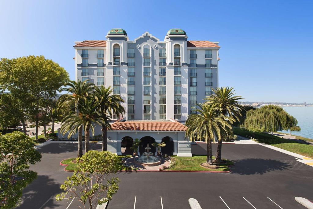 伯林格姆旧金山机场海滨希尔顿合博套房酒店的停车场前方棕榈树的大型建筑